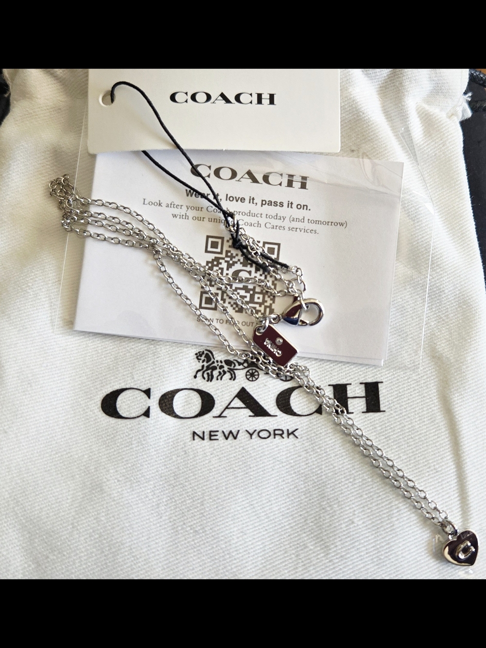 Coach silver-tone necklace features a small, heart pendant with COACH tag